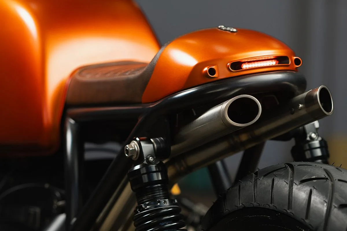 Detalle de la cola naranja de la BMW R100/7 con el piloto LED integrado, los dos silenciosos de acero inoxidable y los amortiguadores traseros negros