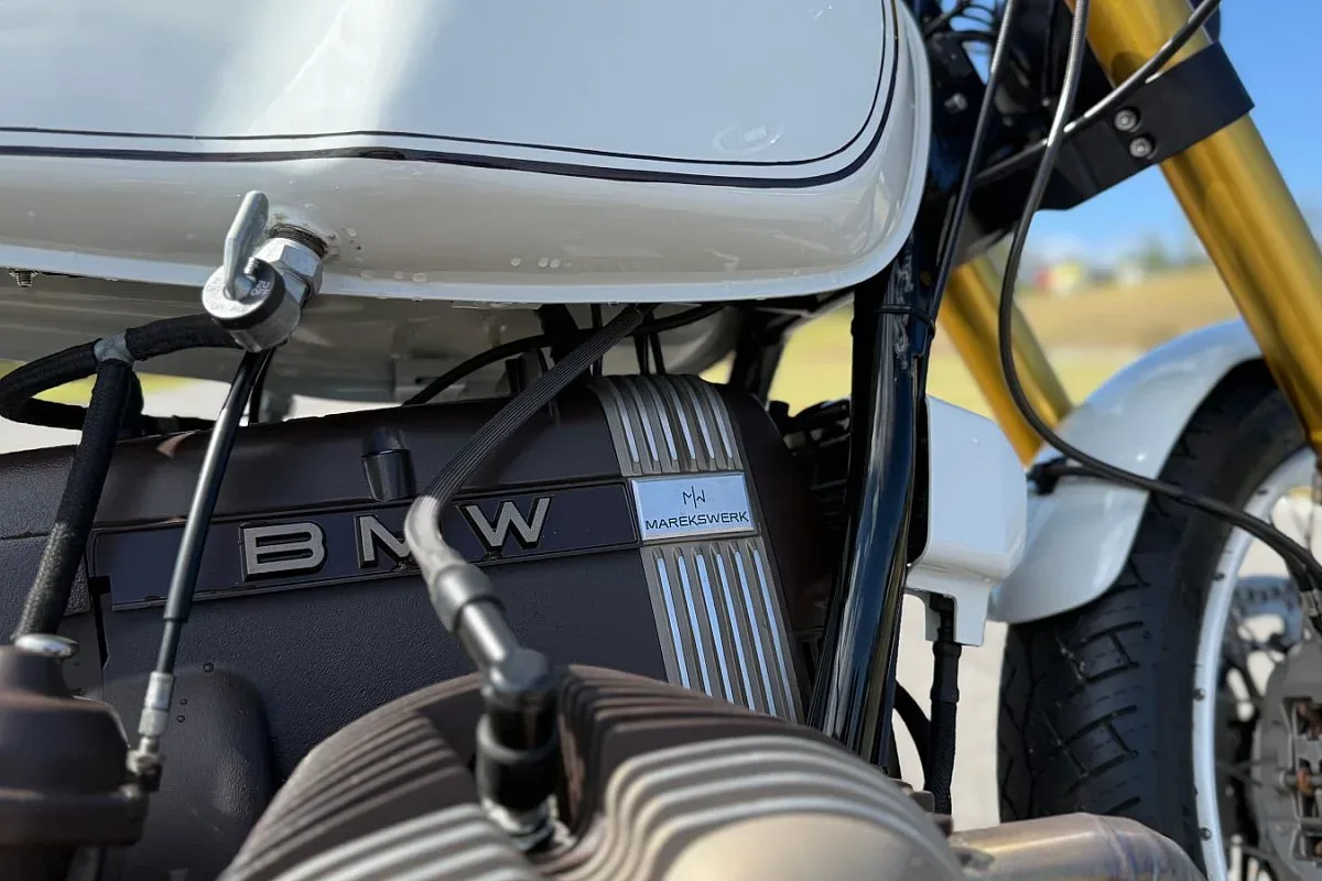 Placa de Marekswerk junto al logotipo BMW en el motor bóxer de la R100 cafe racer, con la horquilla dorada al fondo
