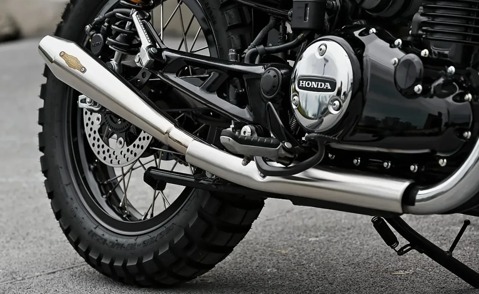 Detalle del escape cromado de cono invertido y de la tapa de motor Honda de la CB350 scrambler