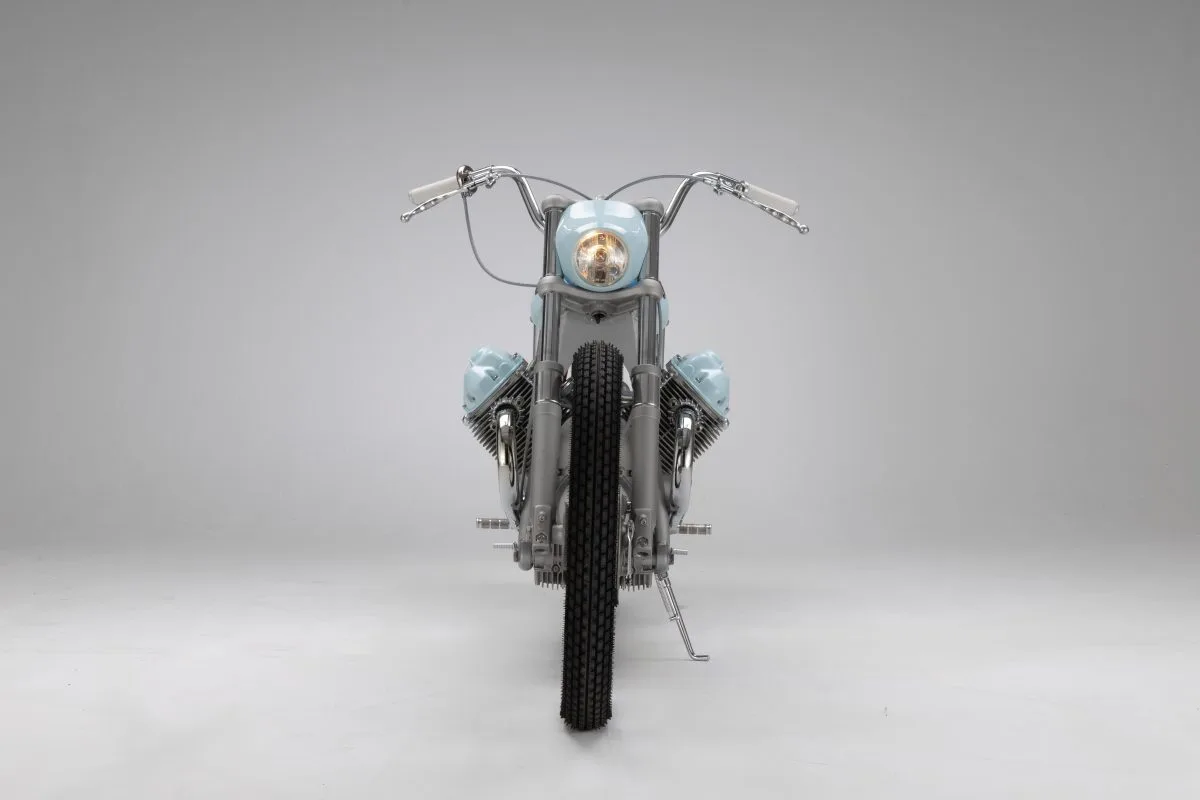 Vista frontal de la Moto Guzzi V7 «Bonanza»: manillar ancho, faro redondo azul claro y los dos cilindros en V asomando a ambos lados